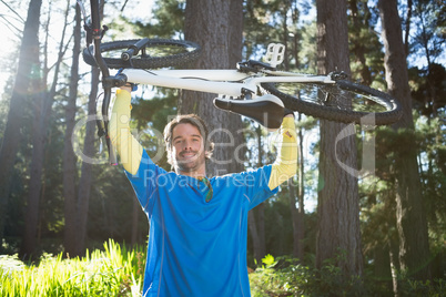 Male mountain biker carrying bicycle in the forest