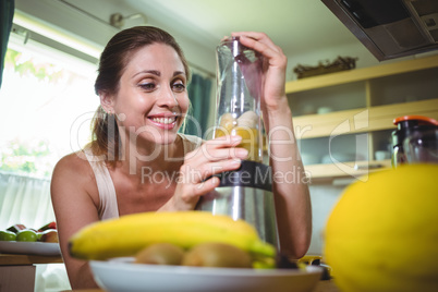 Smiling woman preparing smoothie