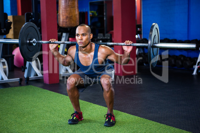 Young man weightlifting in fitness studio