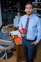 Business executive standing with a cup of coffee