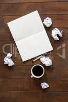 Notepad, pen, crumpled paper and cup of coffee