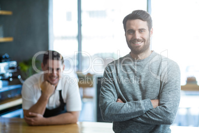 Portrait of man standing with arms crossed at counter