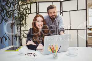 Smiling business people with laptop on desk