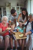 Multi-generation family having pizza in living room