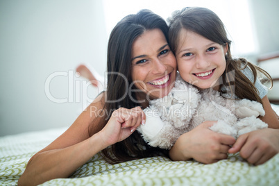 Portrait of mother and daughter lying in bedroom