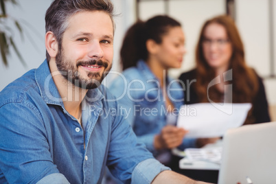 Portrait of smiling businessman against female coworkers