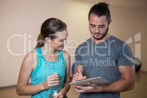 Fitness trainer and woman looking at clipboard