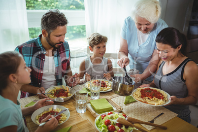 Elderly woman  serving meal to her family