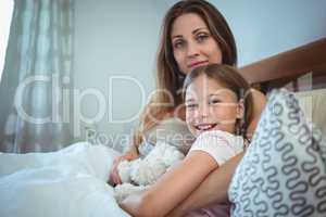 Mother lying with daughter on bed