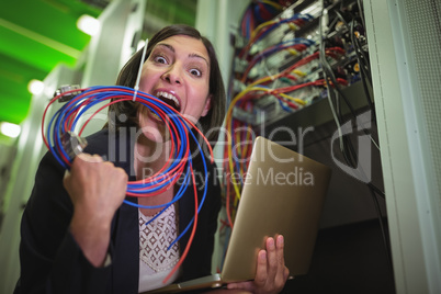 Frustrated technician eating wire and holding laptop