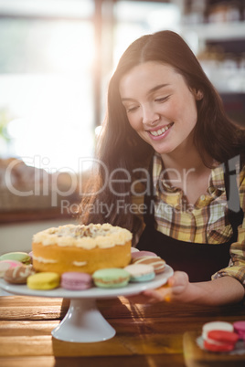 Waitress holding dessert on cake stand in cafe