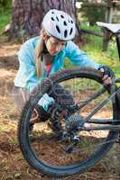 Female mountain biker examining wheel of her bicycle