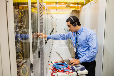 Technician in head phones using laptop