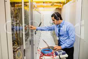 Technician in head phones using laptop