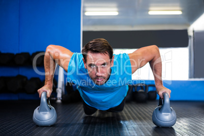 Portrait of serious man doing push-ups with kettlebell