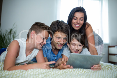 Happy family using digital tablet in bedroom