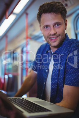 Portrait of handsome man using laptop in train