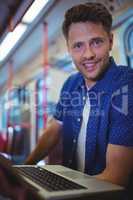 Portrait of handsome man using laptop in train
