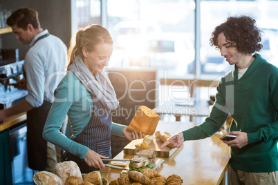 Female waitress packing sandwich in paper bag