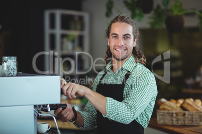 Portrait of smiling waiter making cup of coffee