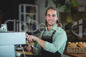 Portrait of smiling waiter making cup of coffee