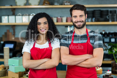 Portrait of smiling waiter and waitress standing at counter
