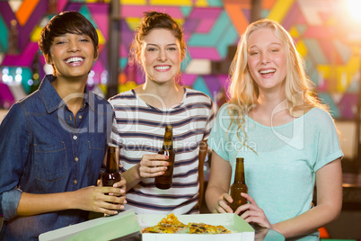 Three female friends having bottle of beer and pizza in party