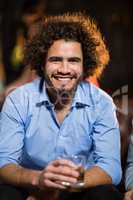 Smiling man holding glass of whisky in bar