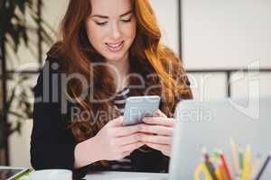 Happy woman using cellphone at creative office