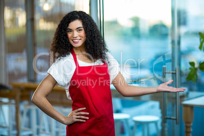 Portrait of smiling waitress standing with hand on hip