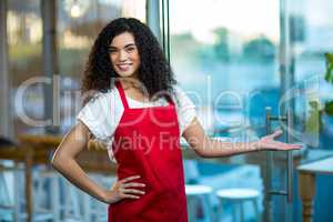 Portrait of smiling waitress standing with hand on hip