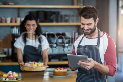 Waiter using digital tablet at counter in cafÃ?Â©