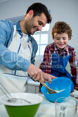 Father teaching his son how to make cup cake