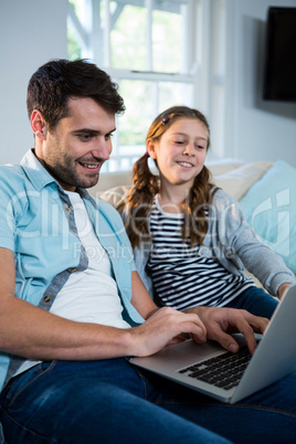Father and daughter using laptop in the living room