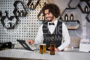 Bartender using digital tablet at bar counter