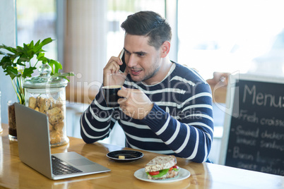 Smiling man talking on mobile phone while having coffee Smiling man talking on mobile phone while having coffee