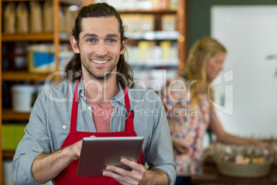 Male staff holding a digital tablet and checking grocery products on the shelf