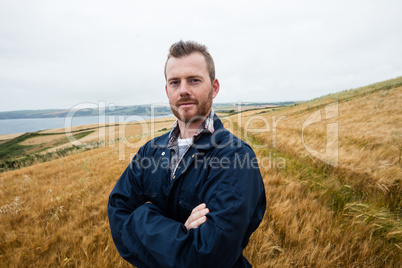 Portrait of farmer standing with arms crossed in the field