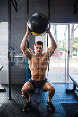 Shirtless young man exercising with ball