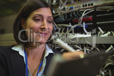 Technician maintaining record of rack mounted server on clipboard