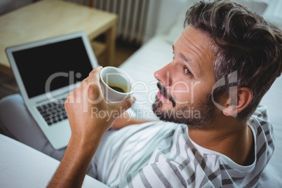 Father using laptop while having coffee in living room Father using laptop while having coffee in living room