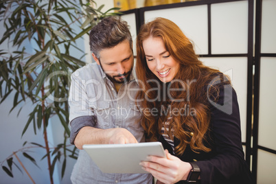 Happy businesswoman with colleague using digital tablet