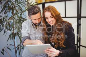 Happy businesswoman with colleague using digital tablet