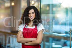 Portrait of smiling waitress standing with arms crossed