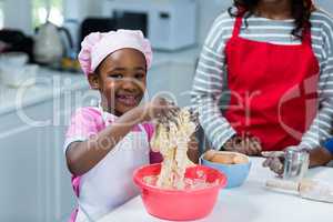 Girl preparing cake with mother