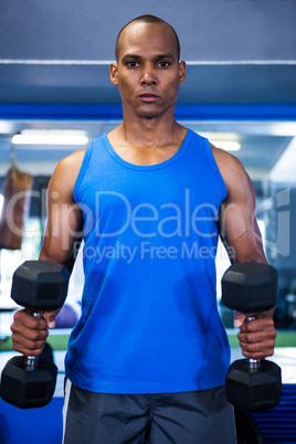 Muscular man exercising with dumbbells