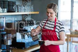 Waitress making cup of coffee at counter in cafe