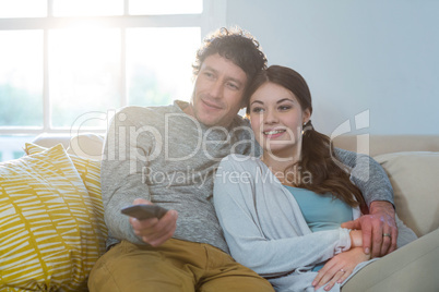 Couple watching television while sitting on sofa