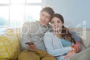 Couple watching television while sitting on sofa