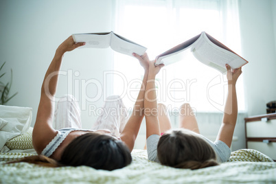 Mother and daughter reading book on bed